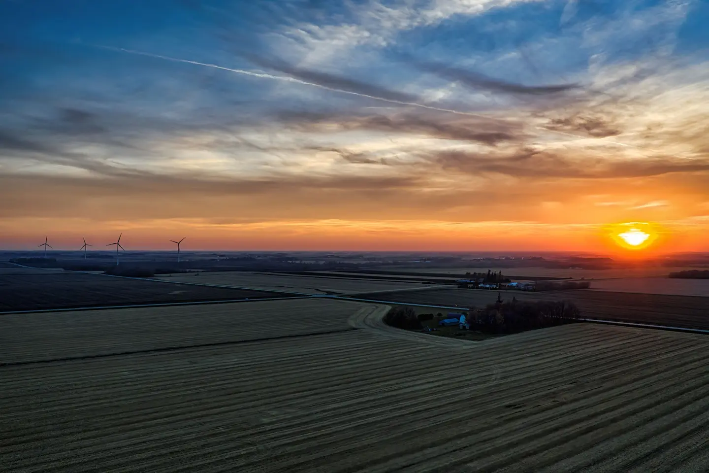 Illustrative scene, not evidence for this record: Wind turbines over farmland at sunset in Minnesota.