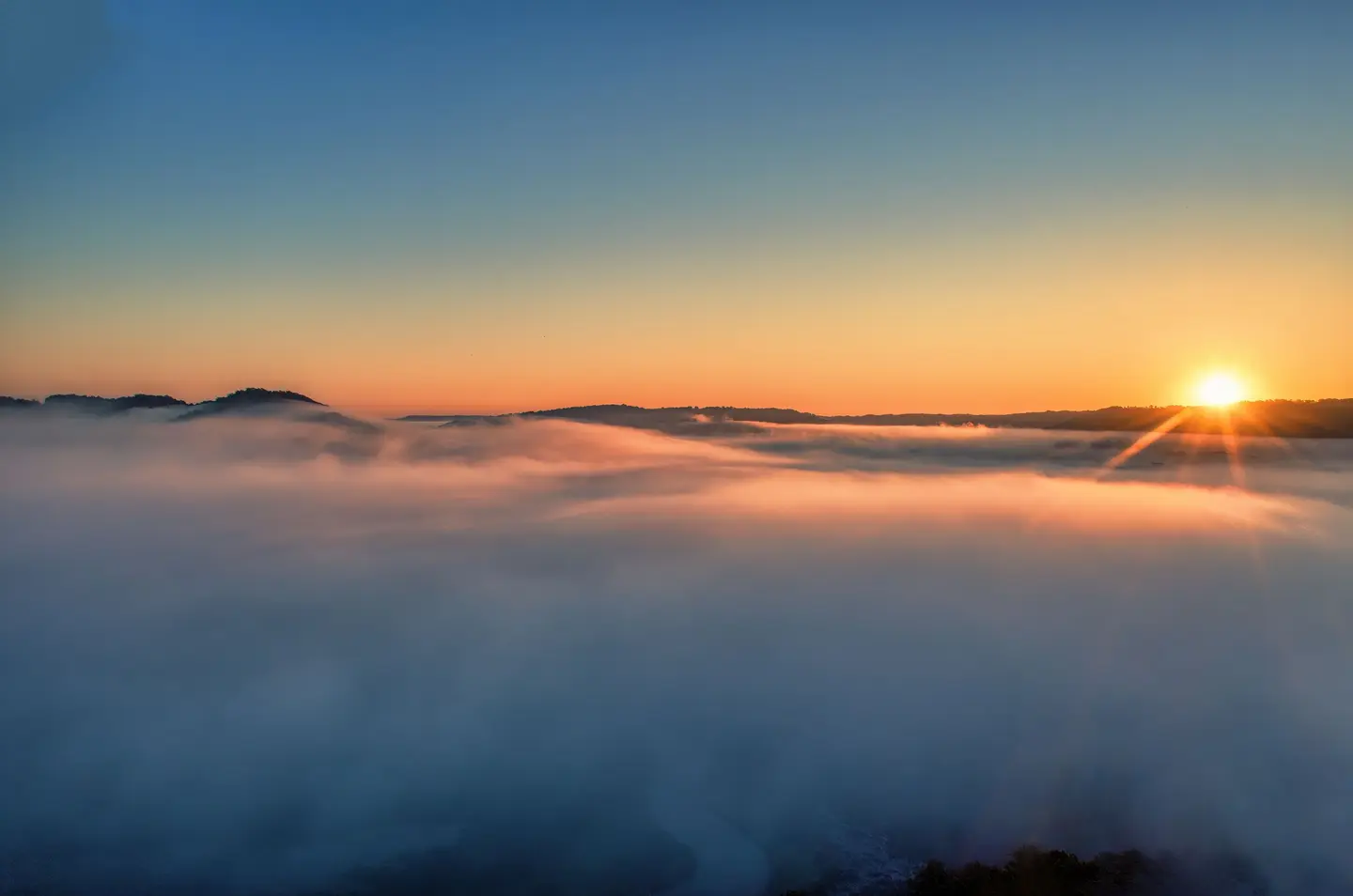 Illustrative scene, not evidence for this record: Sunrise above foggy hills near Tell, Wisconsin.